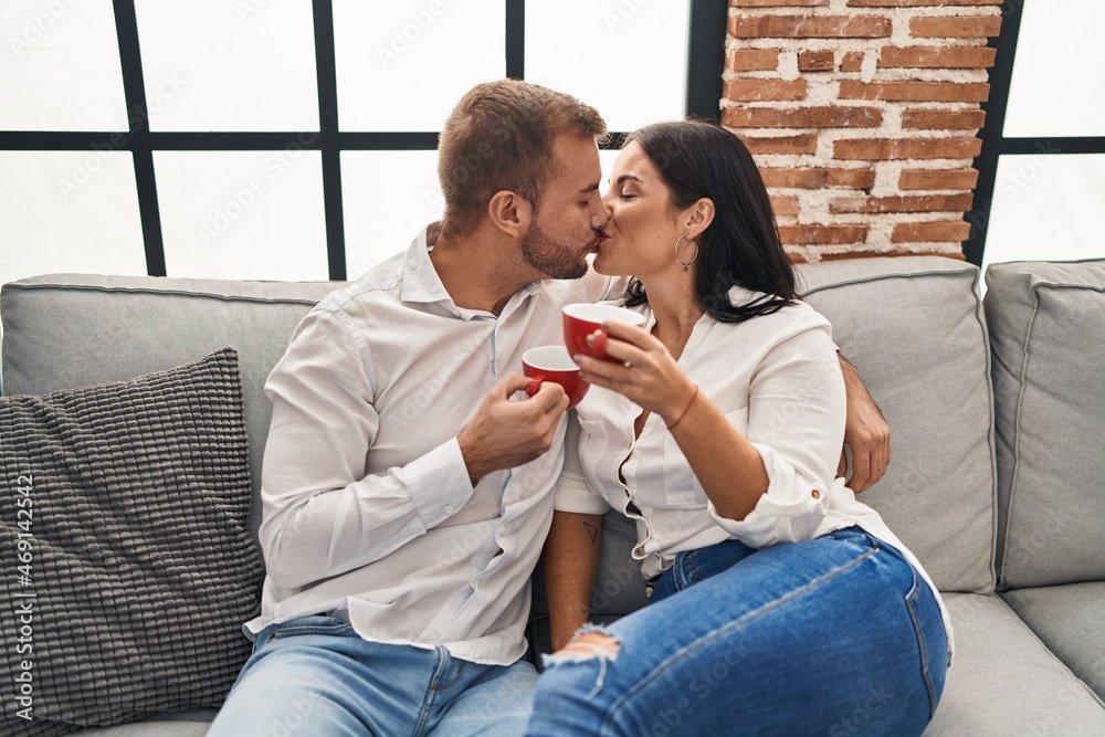 Man and woman couple drinking coffee hugging each other and kissing at home Man and woman couple drinking coffee hugging each other and kissing at home