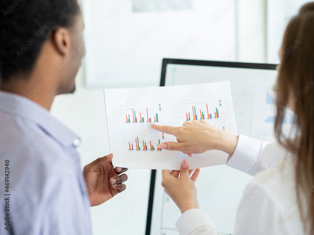 Research data. Working colleagues. Report discussion. Unrecognizable man and woman holding studying documents with graphics in light room interior. Research data. Working colleagues. Report discussion. Unrecognizable man and woman holding studying documents with graphics in light room interior.