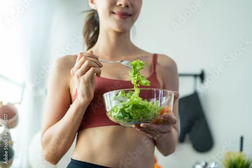 Close up of Asian attractive woman hold salad bowl and eat vegetable. 