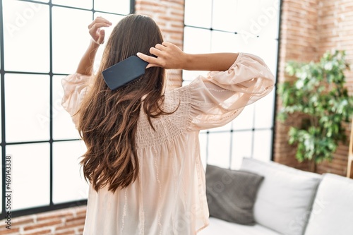 Tableau sur toile Young hispanic woman on back view combing hair at home