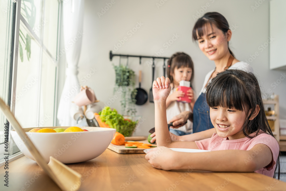 Asian happy family, mother spend time with young daughter in kitchen.