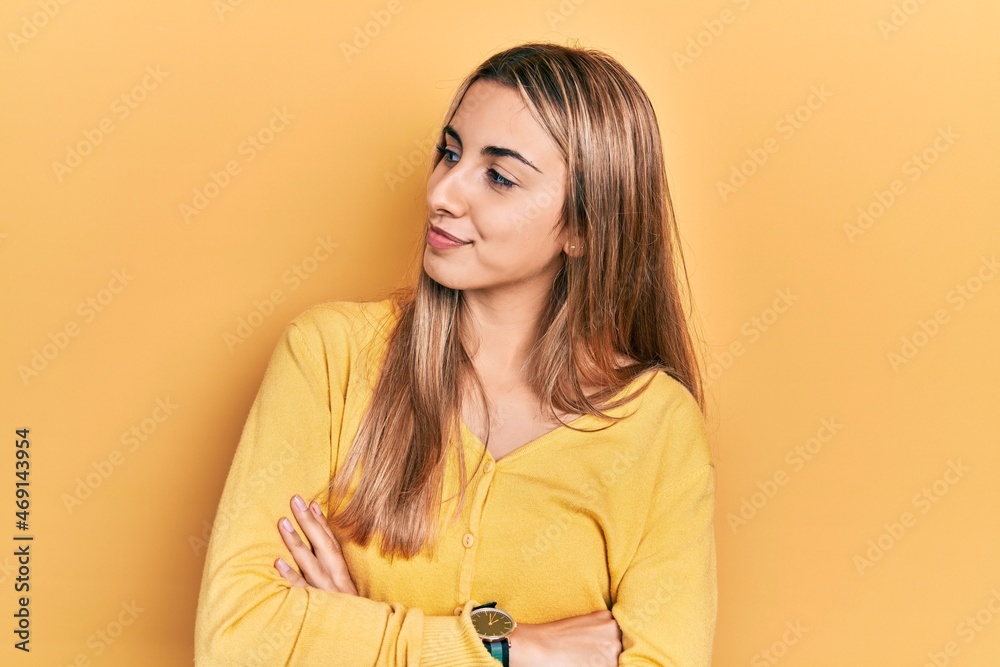 Beautiful hispanic woman wearing casual yellow sweater looking to the side with arms crossed convinced and confident Beautiful hispanic woman wearing casual yellow sweater looking to the side with arms crossed convinced and confident