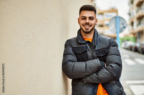 Handsome hispanic man with beard smiling happy and confident at the city wearing winter coat