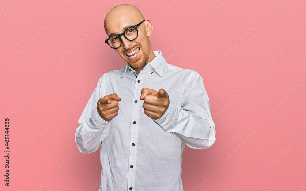 Bald man with beard wearing business shirt and glasses pointing fingers to camera with happy and funny face. good energy and vibes. Bald man with beard wearing business shirt and glasses pointing fingers to camera with happy and funny face. good energy and vibes.