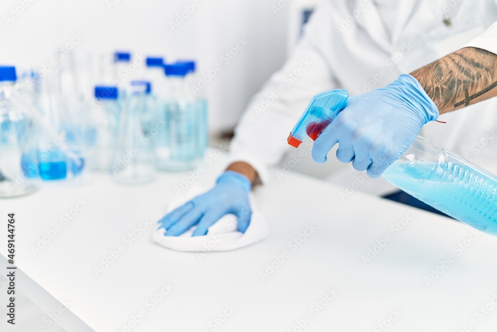 Handsome hispanic man working as scientific cleaning the table at laboratory Handsome hispanic man working as scientific cleaning the table at laboratory