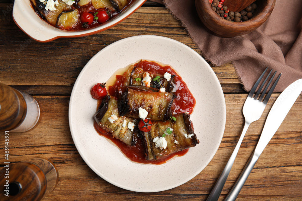 Tasty eggplant rolls served on wooden table, flat lay