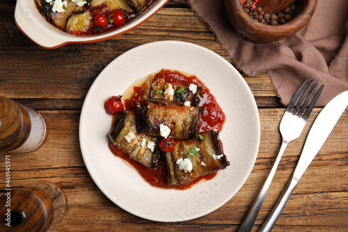 Tasty eggplant rolls served on wooden table, flat lay