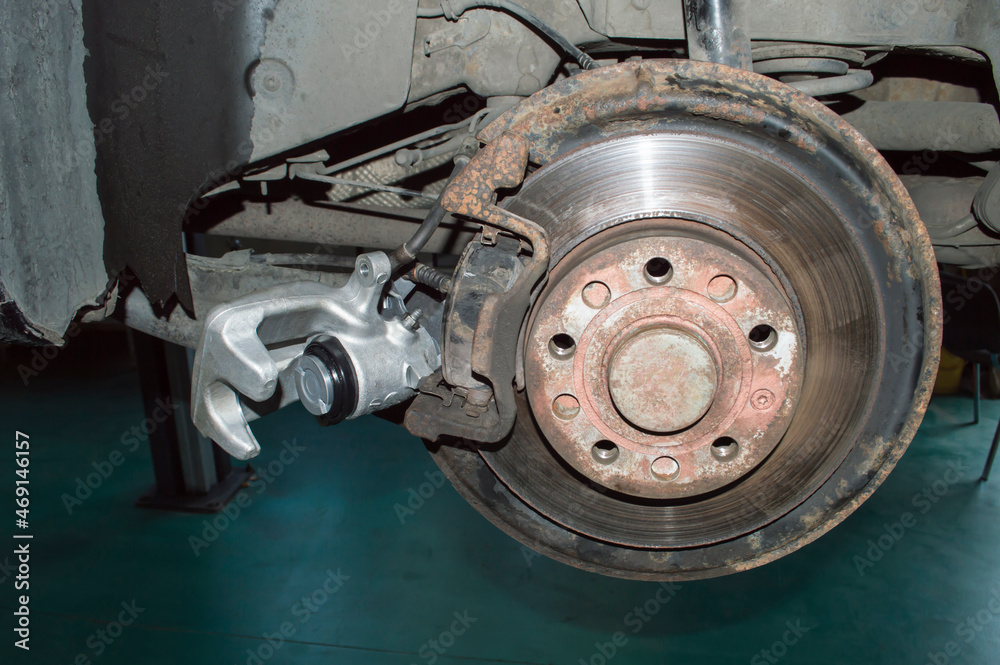 The old rear left brake disc and a new caliper are installed on the car