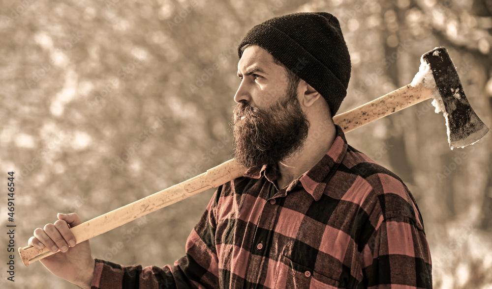 Lumberjack in the woods with an ax. Bearded man in hat with a hatchet.  Handsome man, hipster. Lumberjack brutal bearded man with beard and  moustache on winter day, snowy forest. Photos
