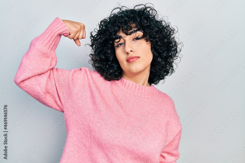 Young middle east woman wearing casual clothes strong person showing arm muscle, confident and proud of power Young middle east woman wearing casual clothes strong person showing arm muscle, confident and proud of power