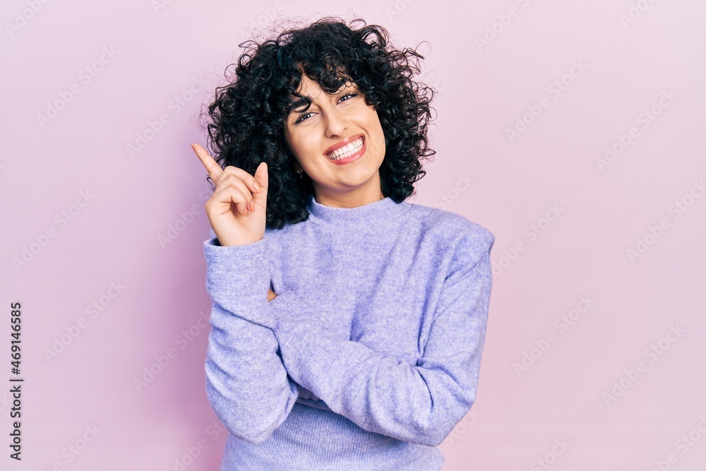 Young middle east woman wearing casual clothes with a big smile on face, pointing with hand and finger to the side looking at the camera. Young middle east woman wearing casual clothes with a big smile on face, pointing with hand and finger to the side looking at the camera.