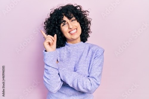 Young middle east woman wearing casual clothes with a big smile on face, pointing with hand and finger to the side looking at the camera. © Krakenimages.com