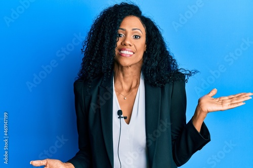Middle age african american woman using lavalier microphone celebrating achievement with happy smile and winner expression with raised hand