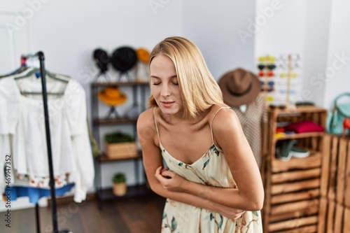 Young caucasian woman at retail shop with hand on stomach because indigestion, painful illness feeling unwell. ache concept.