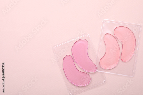 Packages with under eye patches on light pink background, flat lay. Space for text