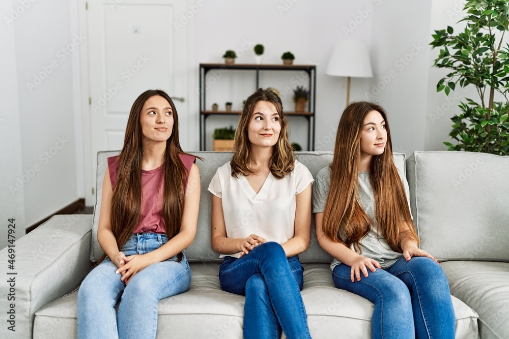 Group of three hispanic girls sitting on the sofa at home smiling looking to the side and staring away thinking. Group of three hispanic girls sitting on the sofa at home smiling looking to the side and staring away thinking.