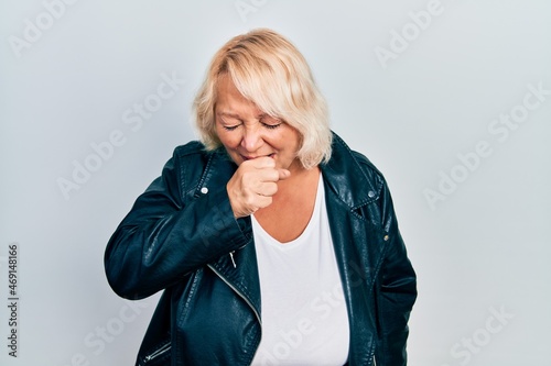 Middle age blonde woman wearing leather jacket feeling unwell and coughing as symptom for cold or bronchitis. health care concept.