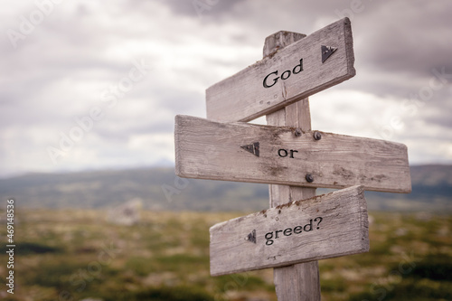 god or greed text on wooden sign outdoors in nature. Religious and christianity quotes.