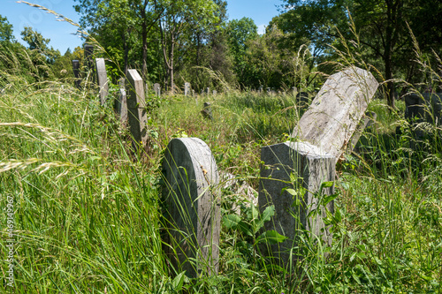 Verlassene Grabsteine im überwuchernden Gras am Friedhof