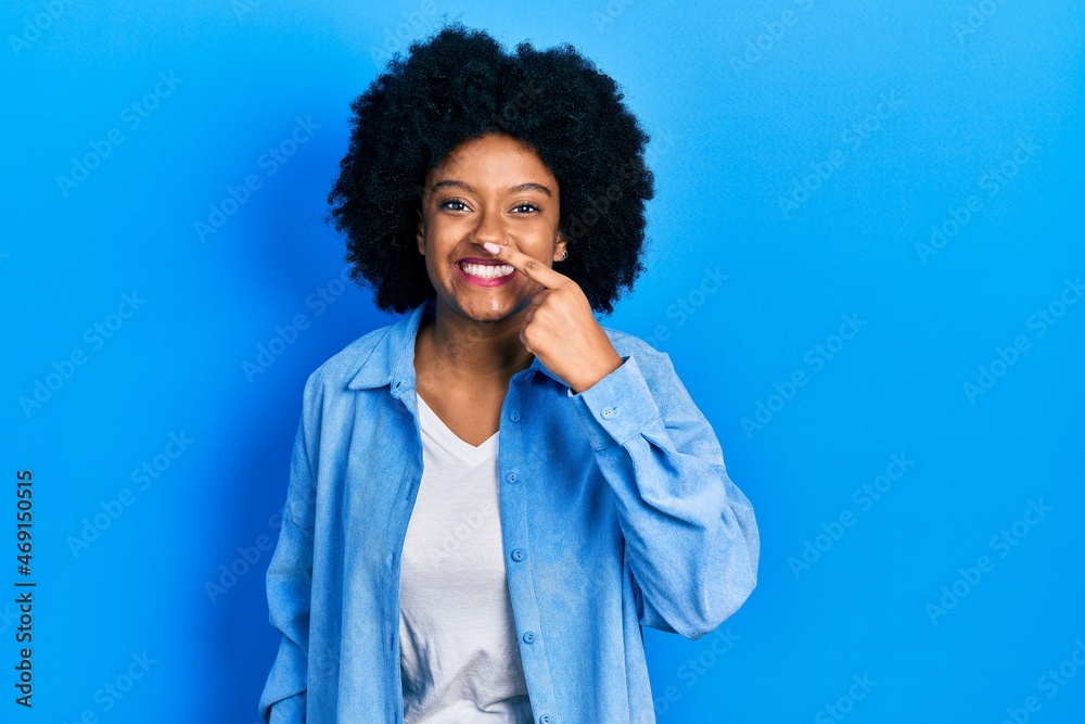 Young african american woman wearing casual clothes pointing with hand finger to face and nose, smiling cheerful. beauty concept Young african american woman wearing casual clothes pointing with hand finger to face and nose, smiling cheerful. beauty concept