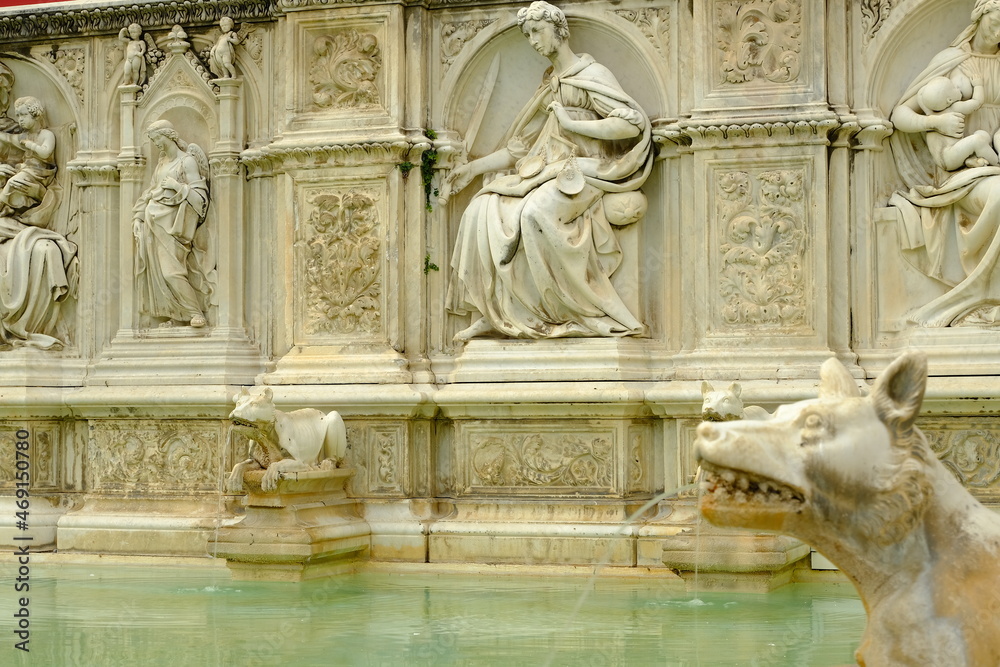 Public fountain. Fonte Gaia fountain in Siena.Reliefs carved in marble on originals by Jacopo della Quercia in Piazza del Campo. Siena, Tuscany, Italy.