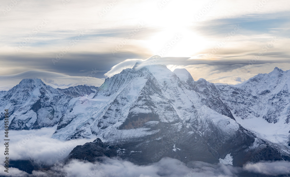 View of the famous peaks Jungfrau, Mönch and Eiger from the Schilthorn in the Swiss Alps over the Lauterbrunnen Valley at sunrise with dramatic clouds and fresh snow.  