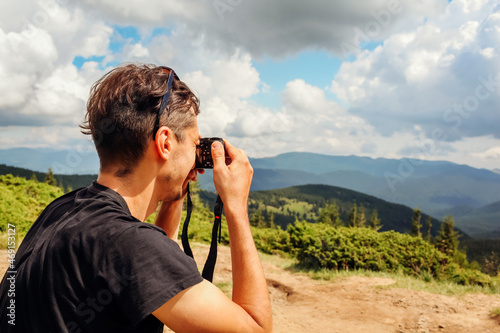 Photographer taking pictures of Carpathian mountains landscape. Man using camera to make photos and footage