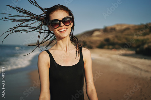 woman walks along the sandy shore in a black swimsuit sun tropics © VICHIZH