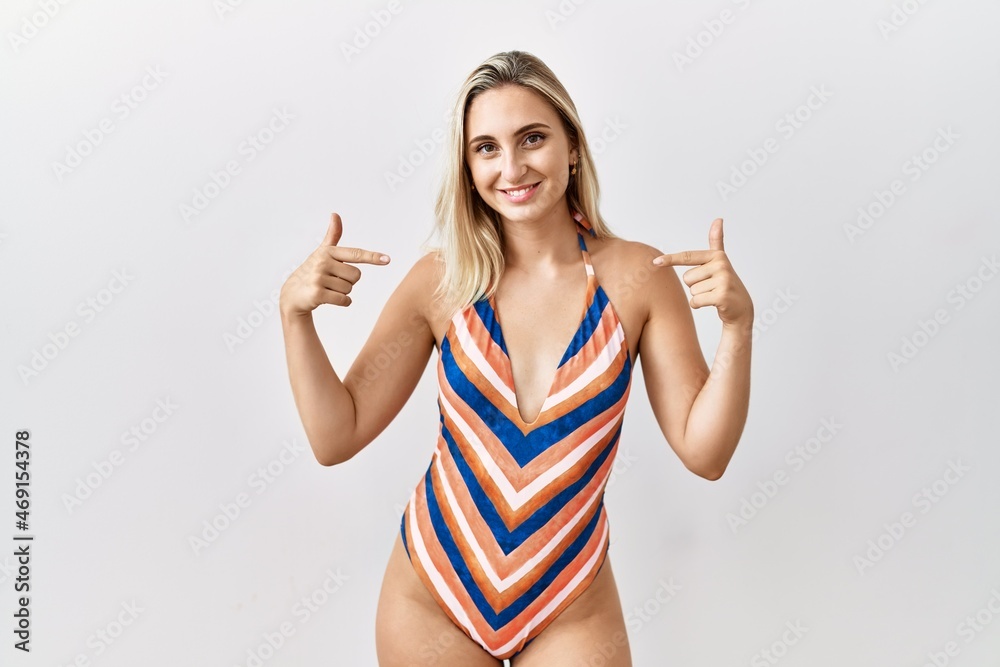 Young blonde woman wearing swimsuit over isolated background looking confident with smile on face, pointing oneself with fingers proud and happy. Young blonde woman wearing swimsuit over isolated background looking confident with smile on face, pointing oneself with fingers proud and happy.