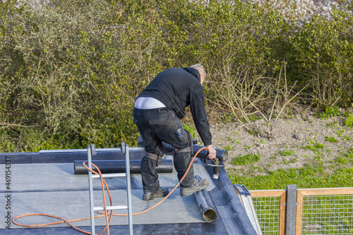 A roofer installing roofing felt with a propane blowtorch