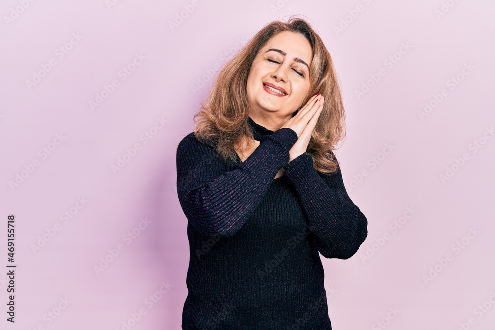 Middle age caucasian woman wearing casual clothes sleeping tired dreaming and posing with hands together while smiling with closed eyes. Middle age caucasian woman wearing casual clothes sleeping tired dreaming and posing with hands together while smiling with closed eyes.