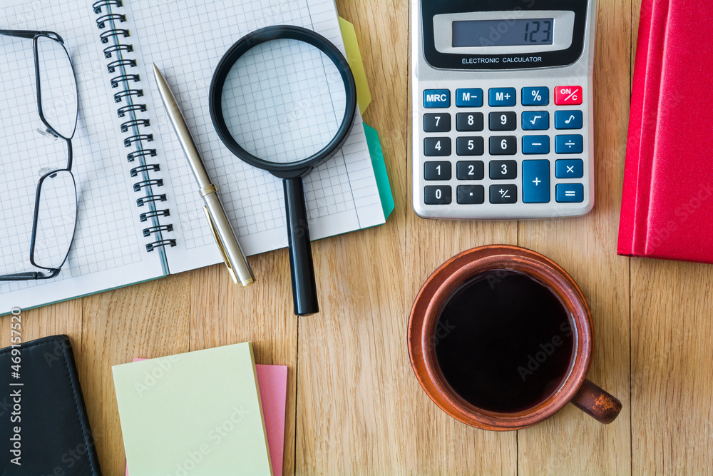 Cup of coffee, notebook with pen, calculator, glasses and other accessories on the desktop Cup of coffee, notebook with pen, calculator, glasses and other accessories on the desktop