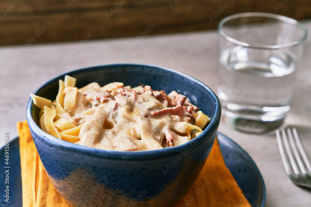 Bowl of fettuccine italian pasta with carbonara sauce on a concrete surface Bowl of fettuccine italian pasta with carbonara sauce on a concrete surface