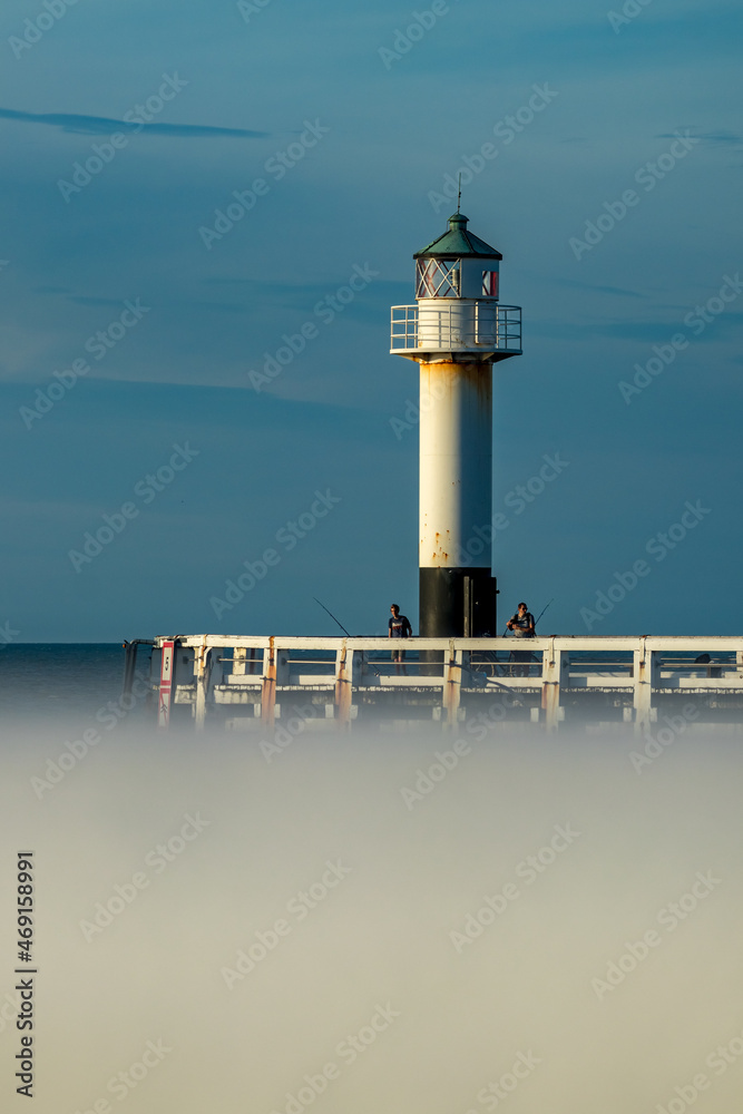 Lighthouse in Belgium. Blurred bottom part peer fence