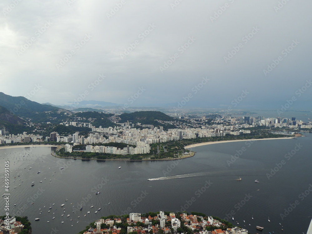 breathless panoramic view of rio de janeiro, crist redentor, favelas and beaches. yacth leaving trails on back. light raysin the sky. cable car going up to mountain