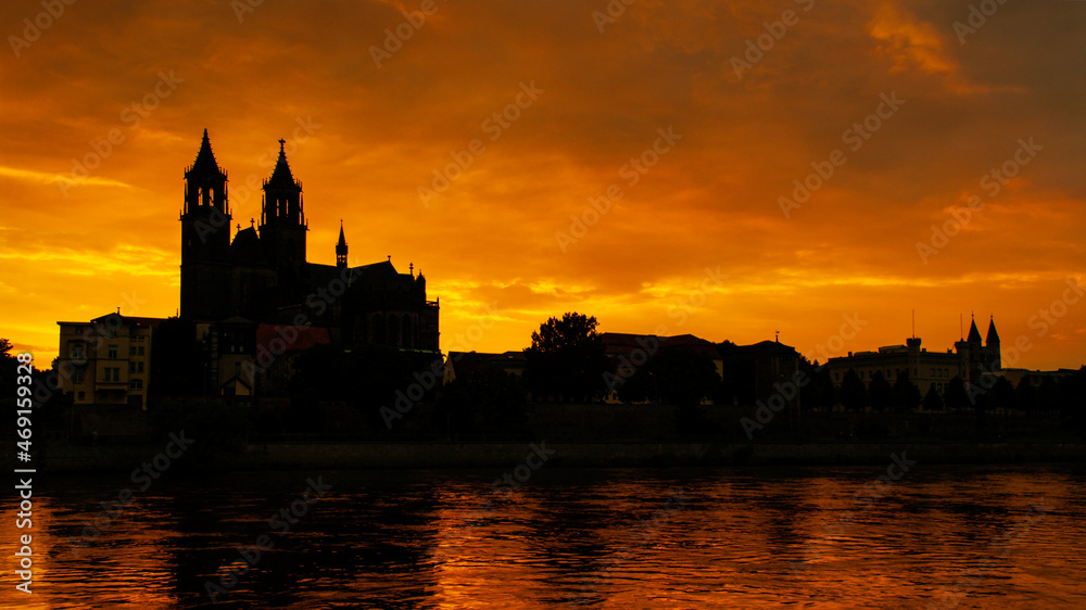 Silhouette of a medieval castle at beautiful bloody sunset at historical downtown of Magdeburg, old town, Elbe river and Magnificent Cathedral, Germany.