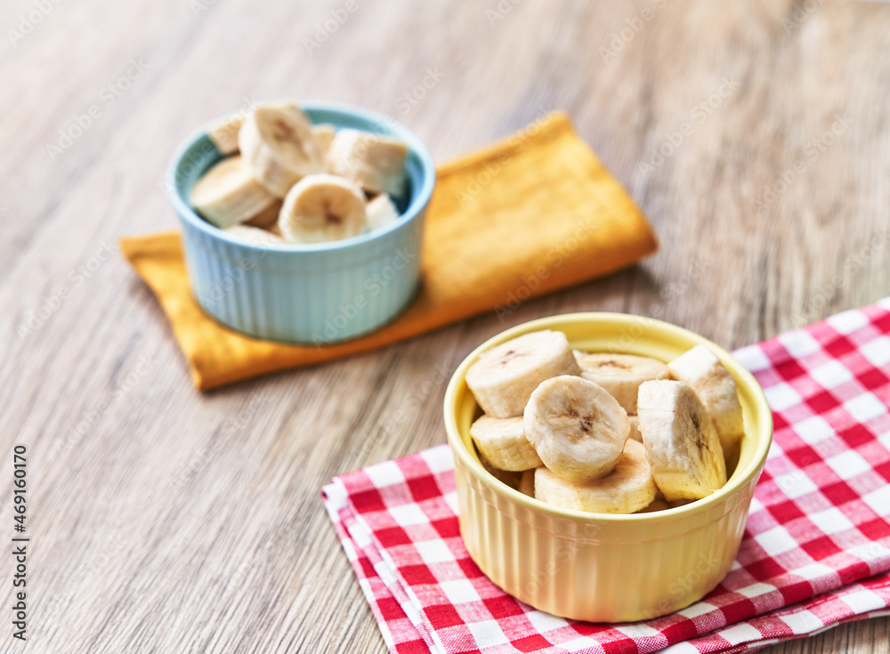 Bowls of slices of banana on a wooden table Bowls of slices of banana on a wooden table