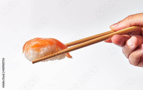  Chopsticks holding single salmon nigiri sushi isolated on white background