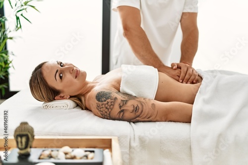 Young caucasian woman at physiotherapy clinic getting muscle massage by professional therapist. Physiotherapist man doing stomach pain treatment to client
