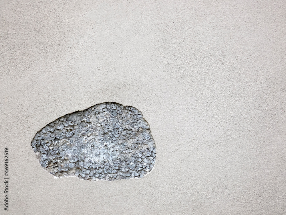 A piece of plaster on the wall has fallen off and a stone wall is visible A piece of plaster on the wall has fallen off and a stone wall is visible