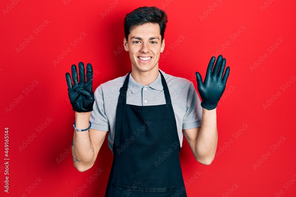 Young hispanic man wearing apron showing and pointing up with fingers number nine while smiling confident and happy. Young hispanic man wearing apron showing and pointing up with fingers number nine while smiling confident and happy.