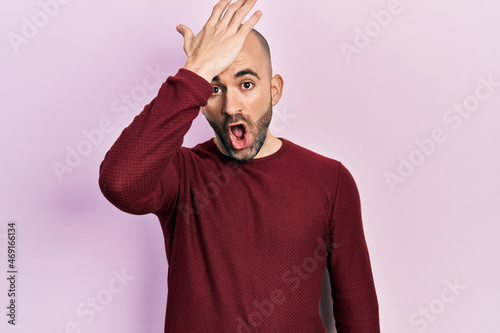 Young bald man wearing casual clothes surprised with hand on head for mistake, remember error. forgot, bad memory concept.