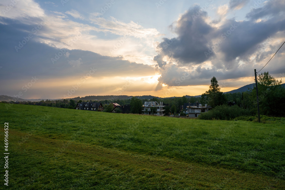 Green meadow field showing countryside view against dramatic sunrise or sunset, in Zakopane, Poland, Europe