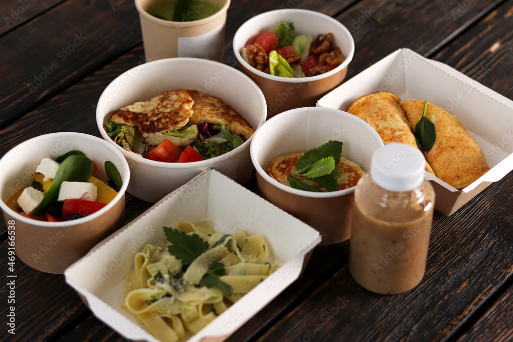 Healthy restaurant food delivery, business lunch and diet plan, fresh daily meals. Daily vegetarian food in eco boxes with copy space in dark wood.