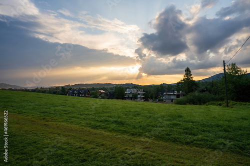 Green meadow field showing countryside view against dramatic sunrise or sunset, in Zakopane, Poland, Europe