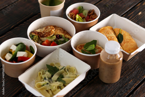 Healthy restaurant food delivery, business lunch and diet plan, fresh daily meals. Daily vegetarian food in eco boxes with copy space in dark wood.