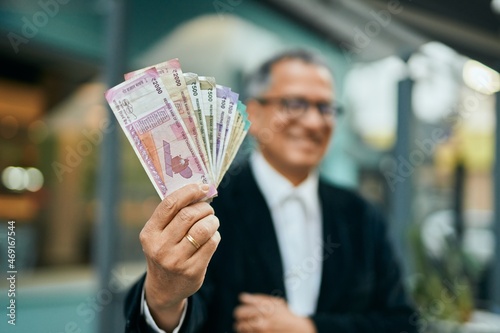 Middle age southeast asian man holding indian rupees banknotes at the city