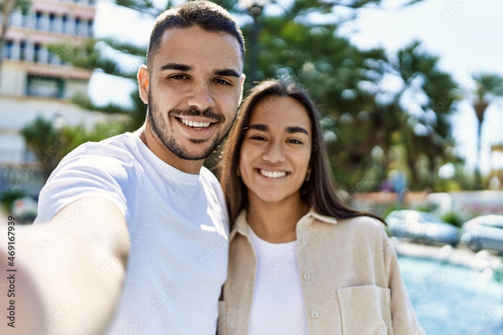 Young latin couple smiling happy and hugging making selfie by the camera at the city. Young latin couple smiling happy and hugging making selfie by the camera at the city.