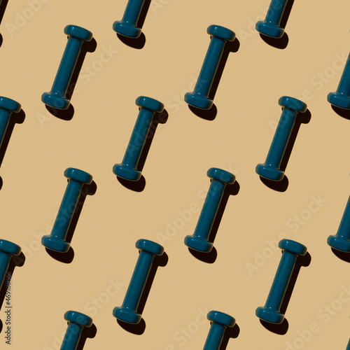 Fitness dumbbells blue on a beige background, pattern, top view.