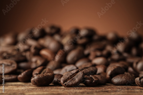 Many roasted coffee beans on wooden table, closeup